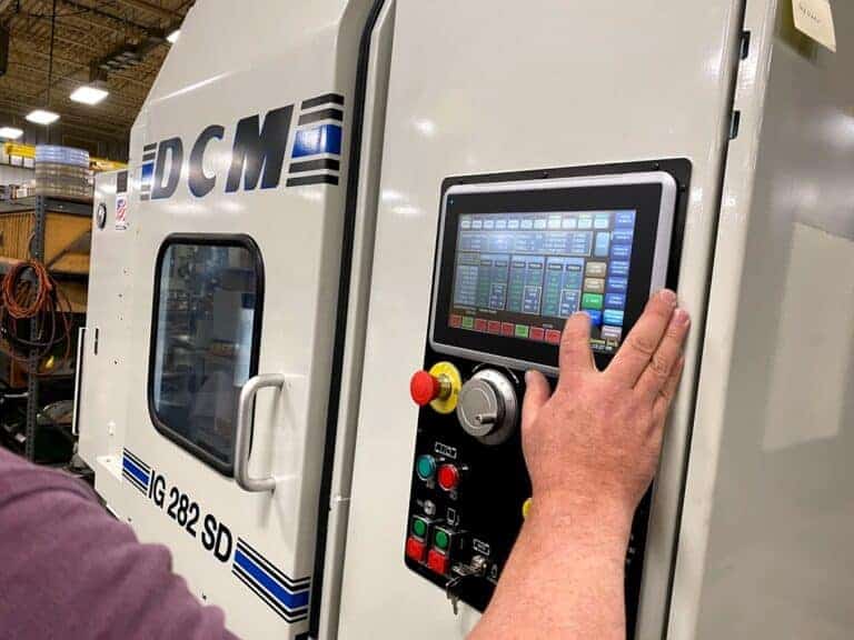 Dcm Tech Employee Using Machine Interface On Industrial Grinder