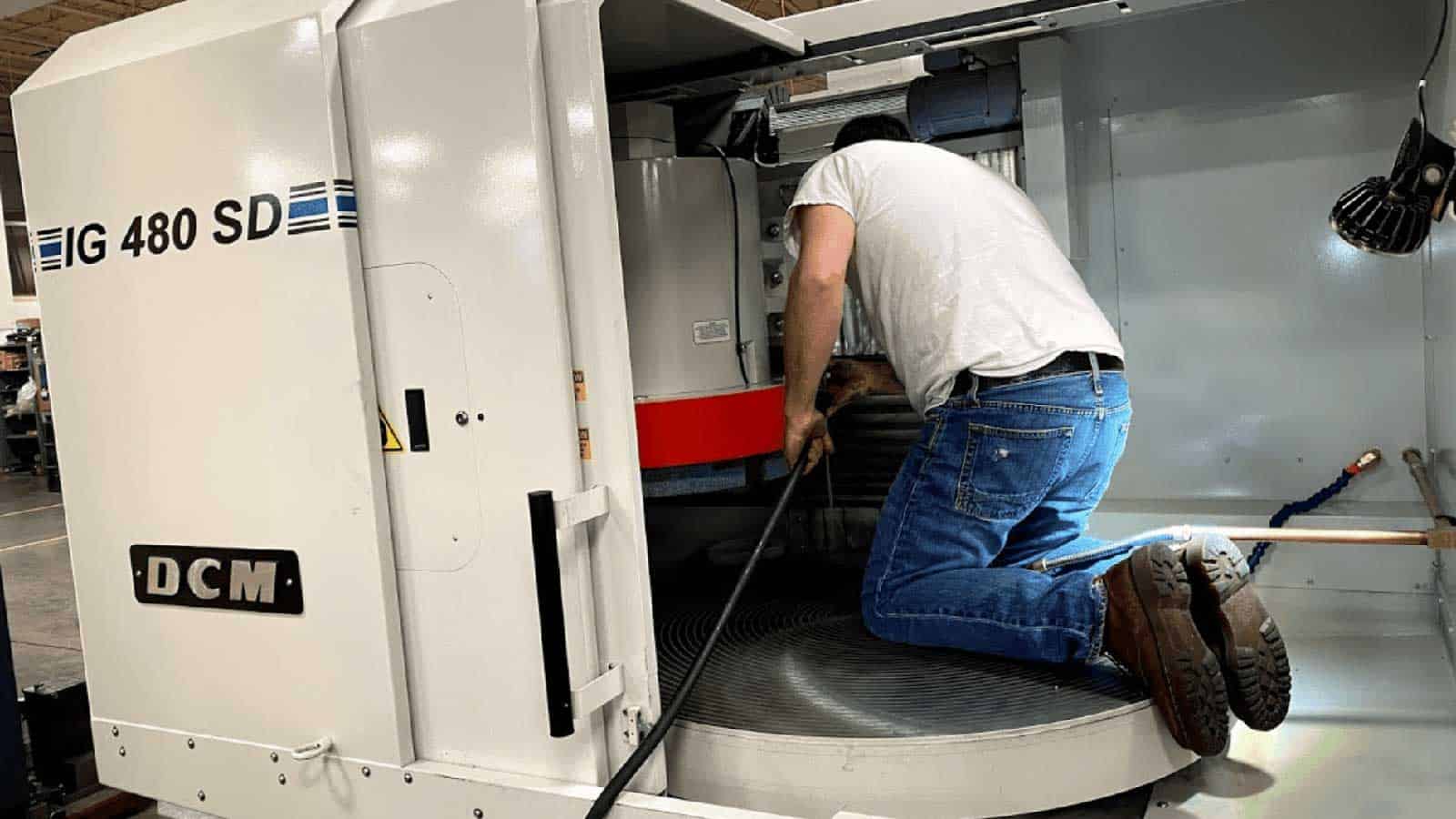 Man Performs Preventative Maintenance On Grinding Machine From Dcm Tech